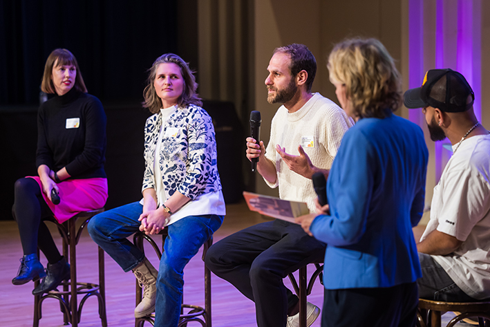 Deelnemers gaan op het podium met elkaar in gesprek.